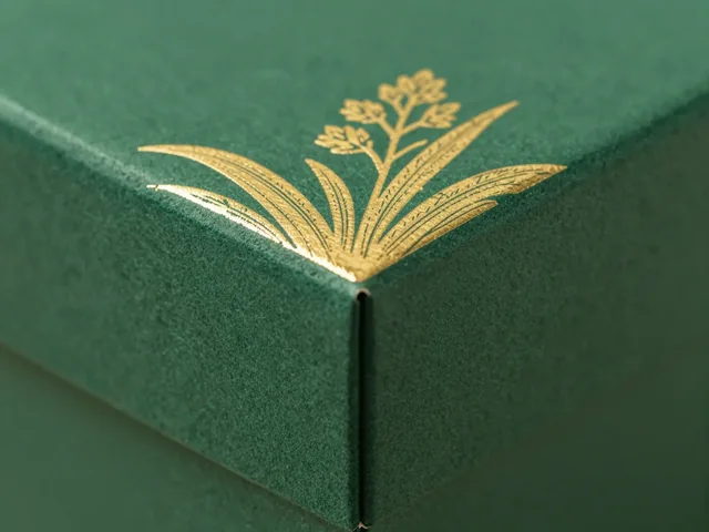Gold hot-foil botanical line art on a green textured rigid box