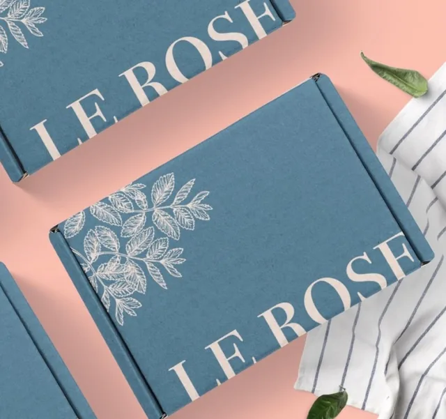 White-ink leaf artwork on a blue corrugated mailer
