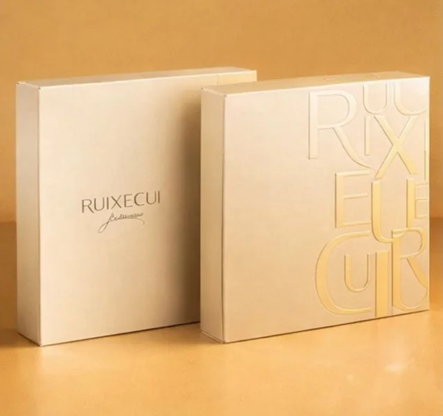 Cream rigid box with blind-embossed lettering and light-gold foil